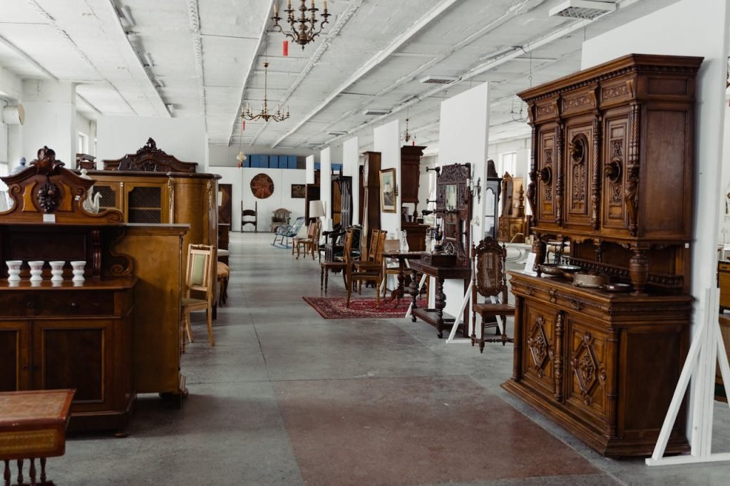 wood-furniture-on-display-in-an-antique-shop-6830012 A spacious showroom filled with various antique wooden furniture pieces on display.